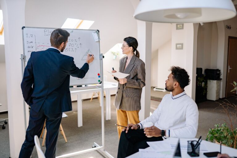 Business consulting advising business owners on a whiteboard.